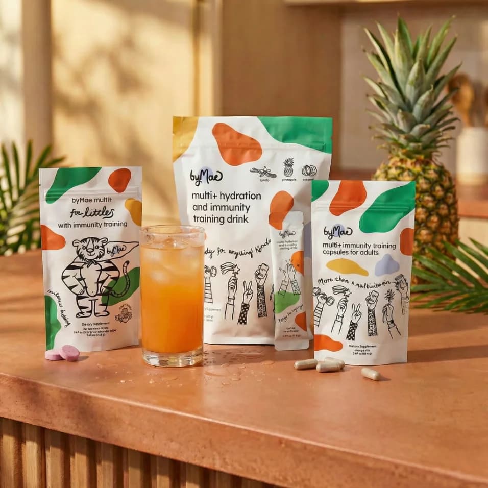 The multi+ for littles, drink and capsules pouches on a counter beside a glass of the drink